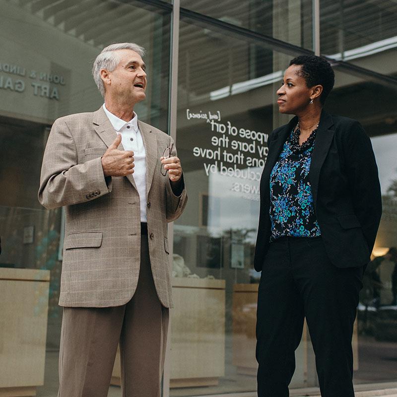 Professor speaking with a student on campus